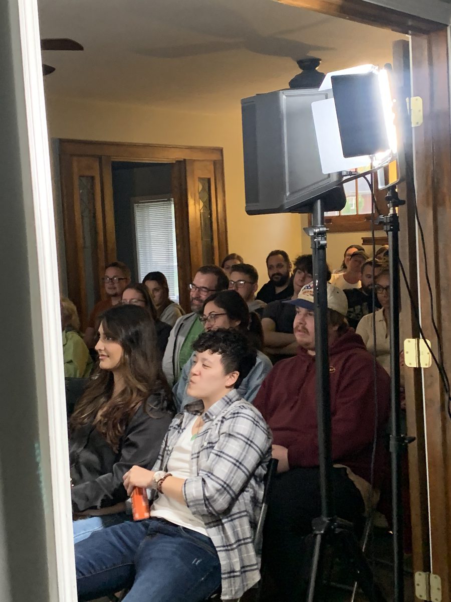 Audience members up close, smiling and reacting during a show in a small room.